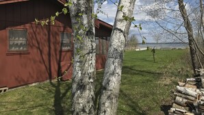 A red building with two windows and a small porch area. - Lake Cabin (Brainerd)