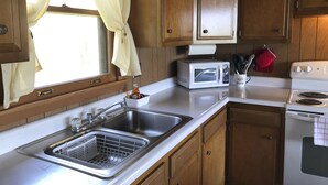 A kitchen with wooden cabinets, a stainless steel sink, a microwave, and a stove. - Lake Cabin (Brainerd)