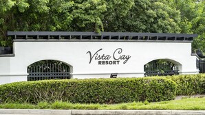 Ein weißes Gebäude mit dem Schriftzug "Vista Cay Resort" und zwei Rundbogenportalen.
