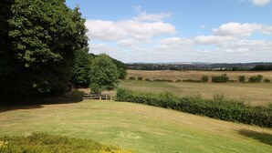 A rural landscape with a grassy field, a wooden fence, and a large tree. - Cedar Holme (Chesterfield)