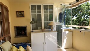 Ein Zimmer mit einer Couch, einem Schrank, einem Kamin, einem Fenster und einem Balkon.