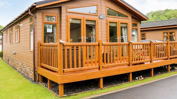 Une cabane en bois dotée d’un balcon, de grandes fenêtres et d’une enseigne indiquant qu’il s’agit d’un hébergement en location avec cuisine.