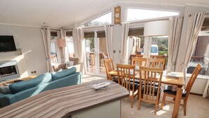 Un vaste espace de vie comprenant un canapé, une table à manger en bois avec des chaises, et un coin cuisine doté d’un plan de travail et de placards.