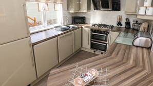 Une cuisine moderne équipée d’un four encastré, d’un four à micro-ondes et d’une cuisinière à gaz.