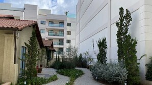 Ein Innenhof mit Kopfsteinpflasterwegen, Kübelpflanzen und einem Gebäude mit Balkonen und Fenstern.