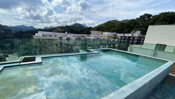 Ein Infinity-Pool auf dem Dach mit freiem Blick auf umliegende Gebäude und Berge.