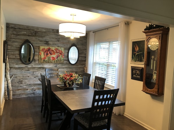A dining area with a wooden wall, a chandelier, and a clock.