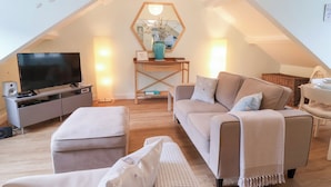Ein gemütliches Loft-Apartment mit großem Fernseher, einem Holztisch, einer bequemen Couch und einer einladenden Sitzecke.