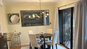 A dining area with a round table, four chairs, a chandelier, and a large mirror on the wall. - Charming Pinehurst Golf Front Condo (Pinehurst)
