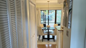 A hallway leading to a dining area with a table and chairs, a rug, and a painting on the wall. - Charming Pinehurst Golf Front Condo (Pinehurst)