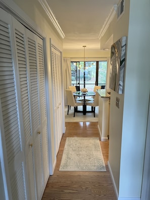 A hallway leading to a dining area with a table and chairs, a rug, and a painting on the wall. - Charming Pinehurst Golf Front Condo (Pinehurst)