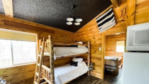 Une cabine équipée de trois lits superposés, d’un réfrigérateur et d’un intérieur en bois.