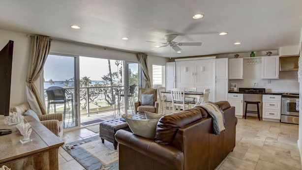 A spacious living area with a leather sofa, a dining table, and a view of the ocean. - Ocean Front View - Steps from the beach! (San Diego)