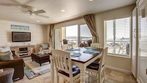 A dining area with a table, chairs, and a view of the city. - Ocean Front View - Steps from the beach! (San Diego)
