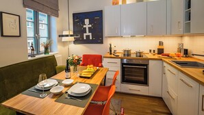 Une cuisine moderne avec des meubles blancs, une table à manger en bois et une chaise rouge.