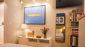 Une chambre à coucher moderne avec un lit, une table de chevet, une lampe et une bibliothèque.