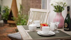 Une table dressée avec des tasses blanches, un verre, une bouteille et un vase contenant des fleurs blanches.