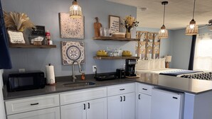 Eine moderne Küche mit weißen Schränken, einer Mikrowelle, einer Kaffeemaschine und Dekoration an der Wand.