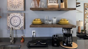 Eine moderne Küche mit Spüle, Toaster, Kaffeemaschine und Dekoration auf Regalen.