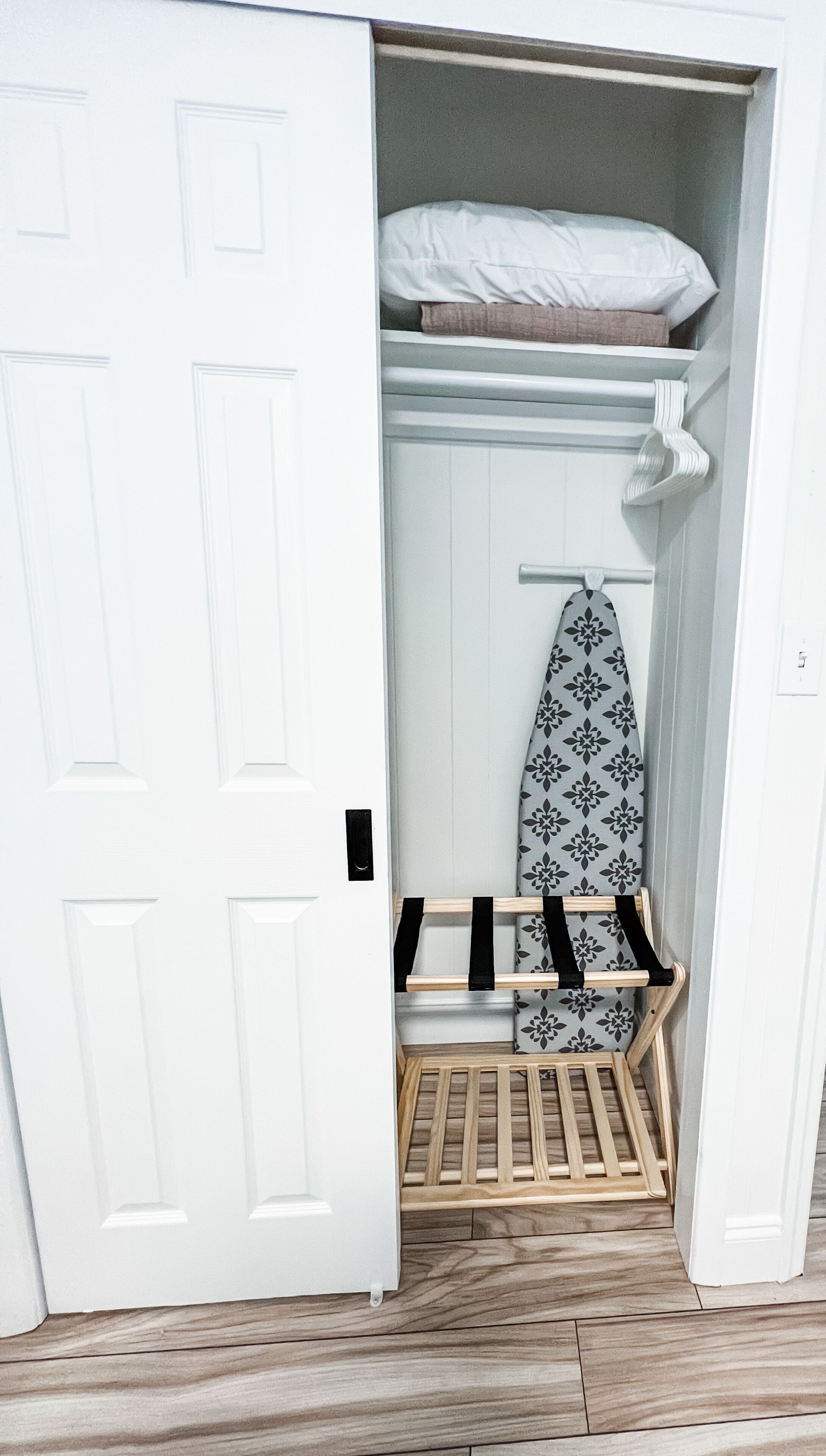 A walk-in closet with a wooden bench, a surfboard, and a hanging rack.