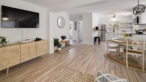 Una cocina moderna con horno integrado, refrigerador y comedor con mesa y sillas de madera.