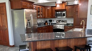 A modern kitchen with wooden cabinets, a stainless steel refrigerator, a built-in oven, and a granite countertop. - Luxury Cottage in Alex Bay 3 bedrooms, 2.5 baths.  Book your 2026 Vacation Now!! (Alexandria Bay)