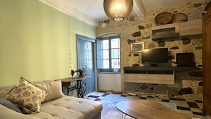 Un salon chaleureux avec un canapé, une petite table, une machine à coudre et un mur en pierre.