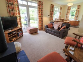 A living room with a television, sofa, ottoman, and a dining area with chairs and a table.