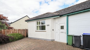 A residential building with a white exterior, a garage door, and a paved driveway. - Limhus Cottage (Keswick)