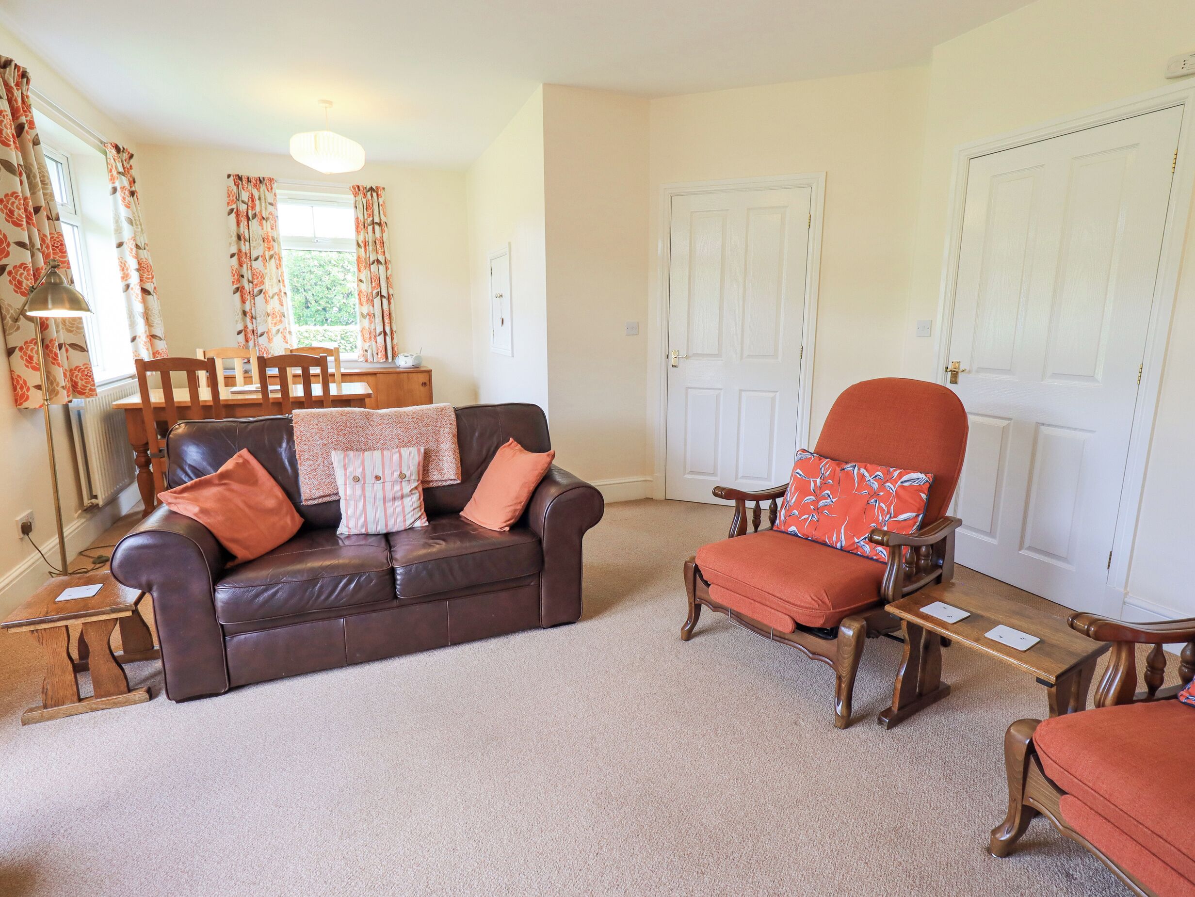 A living room with a brown leather sofa, a wooden armchair, and a dining table with chairs.