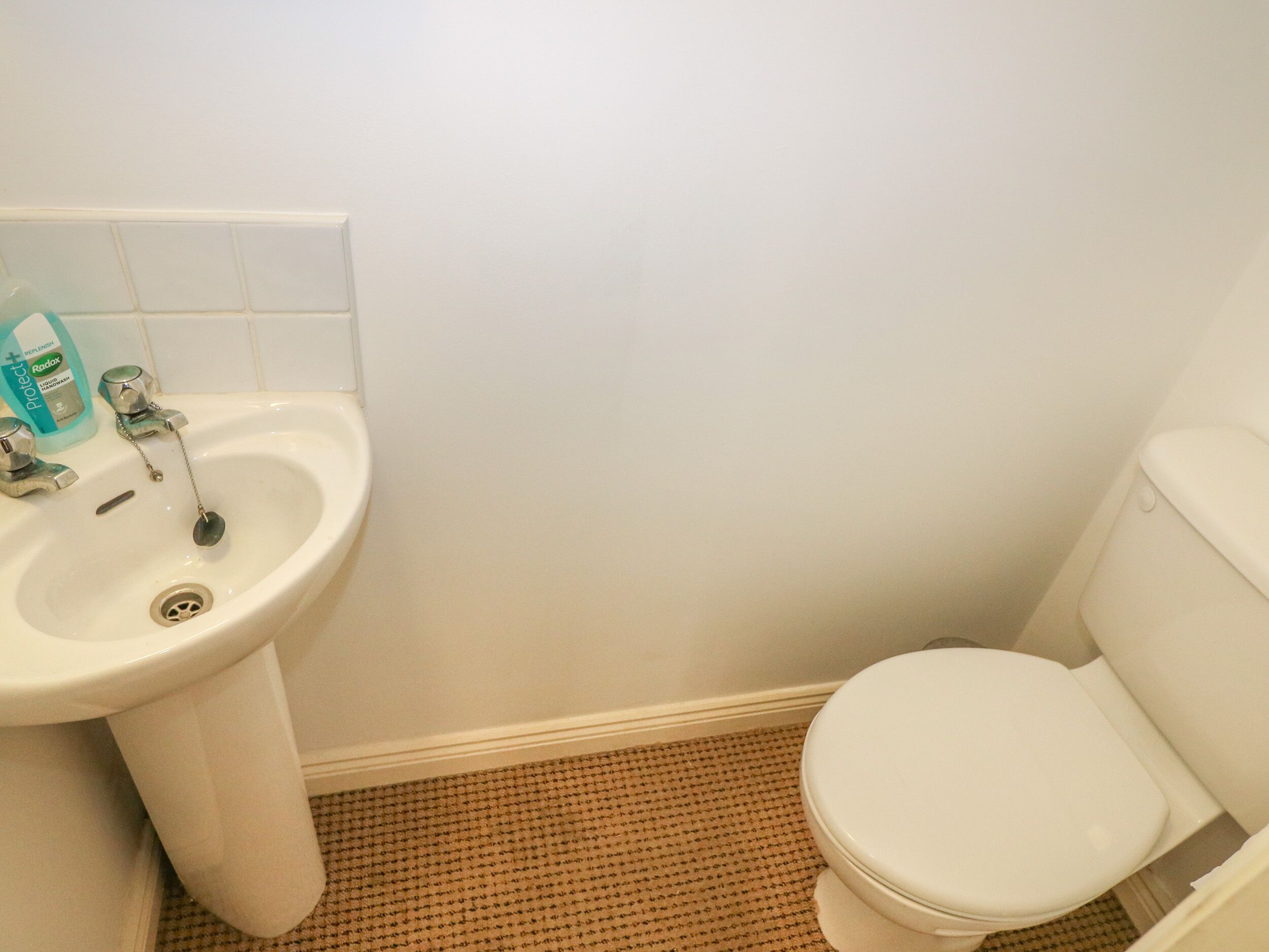 A bathroom with a white sink, a toilet, and a tiled floor.