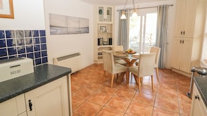 A kitchen with a dining table, chairs, a bread box, and a radiator. - 1 Closheen Lane (Rosscarbery)