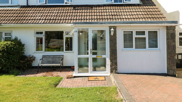 A two-story house with a tiled roof, a front porch, and a bench. - 53 St. Brides View (Haverfordwest)