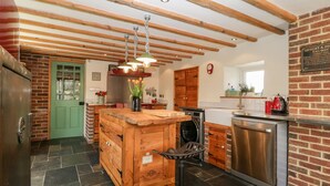 Een keuken met houten balken, een groene deur, een spoelbak, een fornuis en een koelkast.