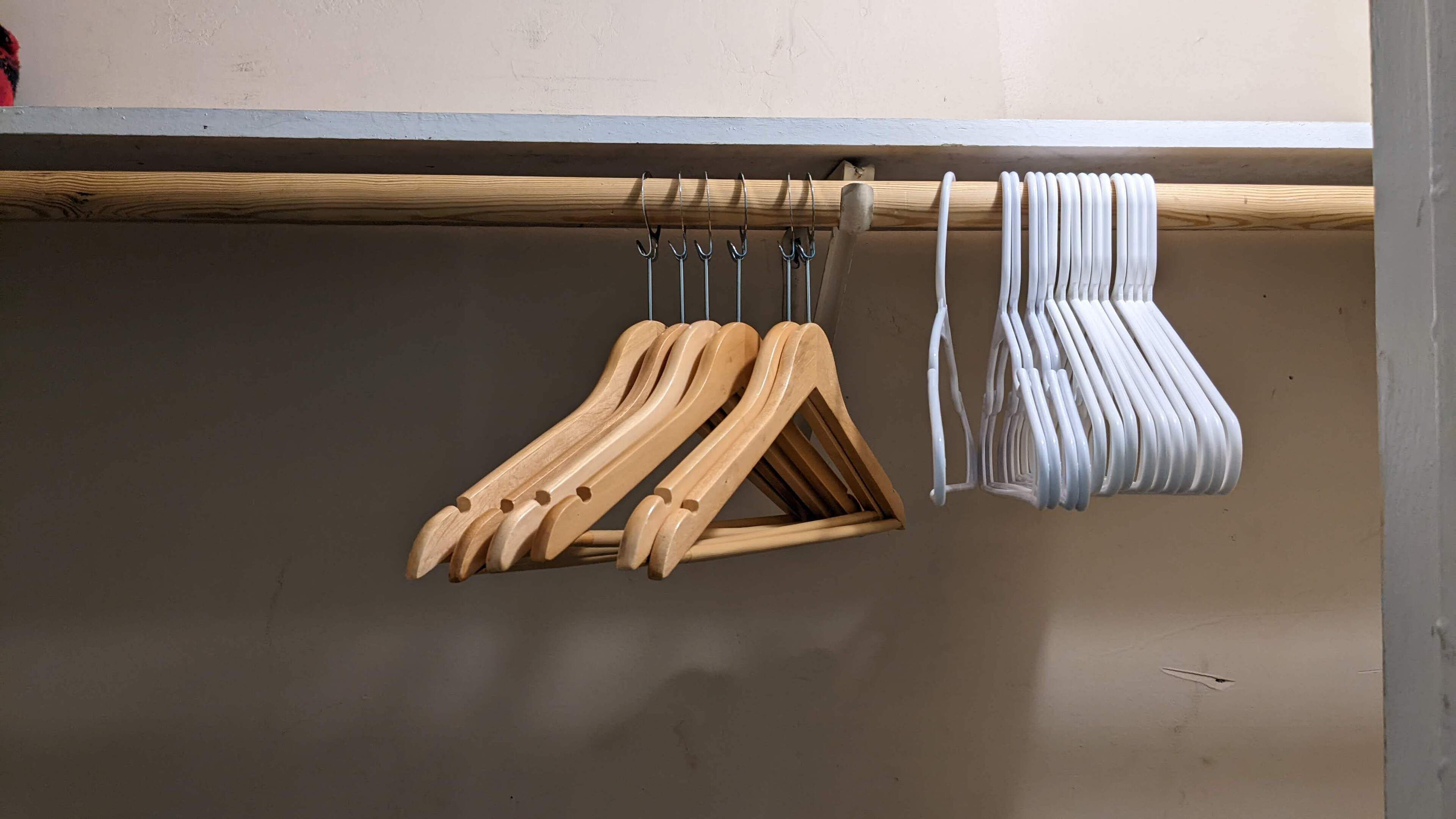 A wooden hanger rack with multiple wooden and white hangers.