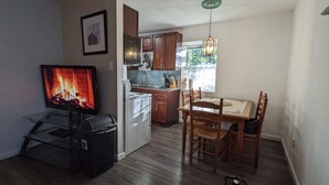 Ein Wohnzimmer mit Kamin, Fernseher und Essbereich mit Holzsesseln und Tisch.