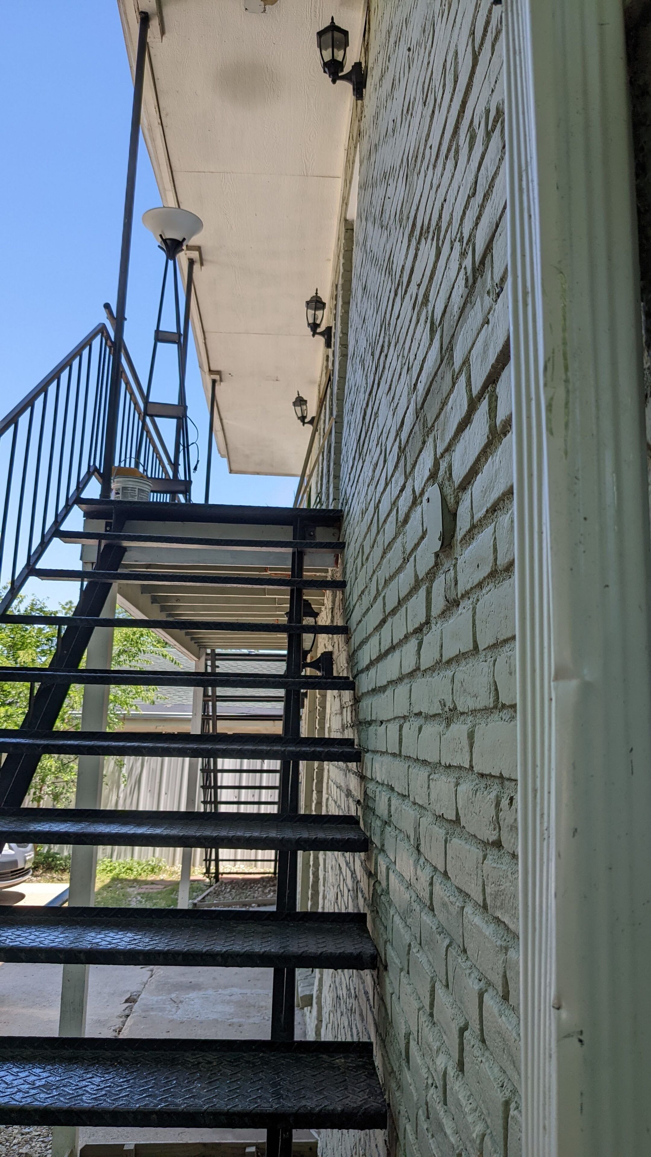 A staircase with a metal railing leading up to a building with a brick wall.