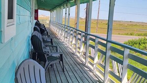 A covered porch with rows of chairs and a view of the landscape. - The Mark at Surfside, Apt. 9 (Surfside Beach)