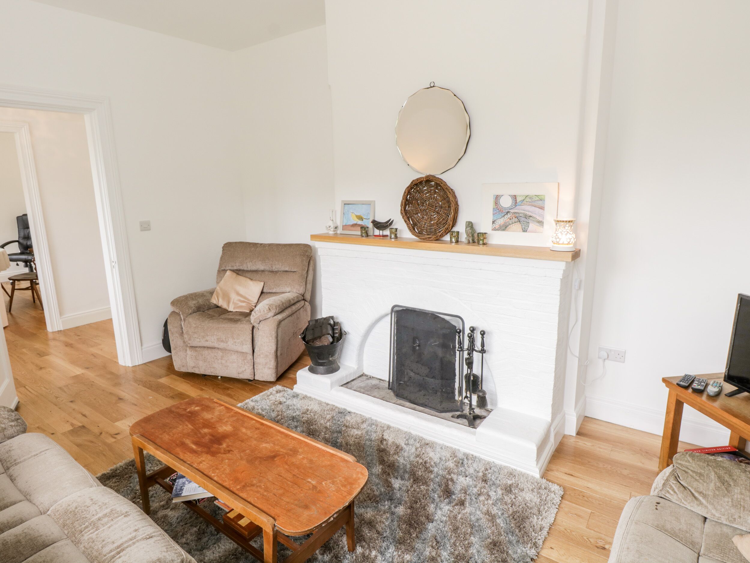Un salon avec une cheminée, un canapé, un fauteuil et une table en bois.