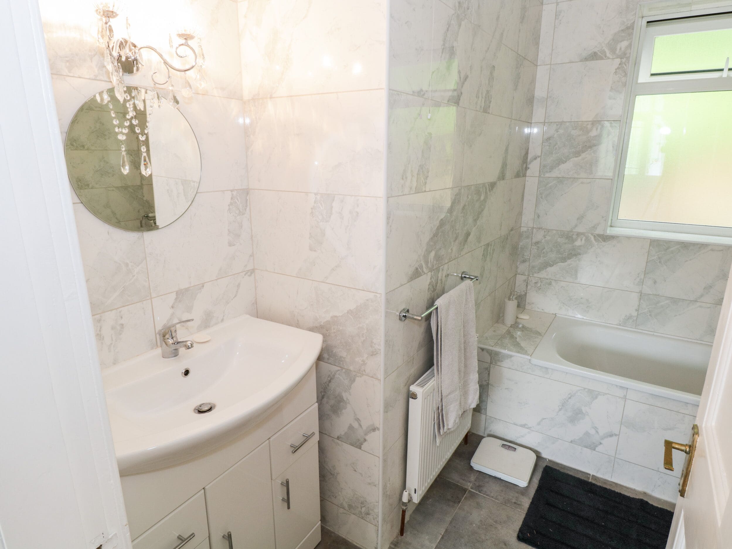 A bathroom with a white sink, a mirror, a towel rack, a toilet, and a bathtub.