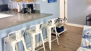 Une cuisine moderne avec un coin bar, des tabourets de bar blancs et une machine à café.