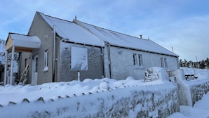 A two-story building with a sloped roof, a porch, and a signboard. - Talla Hope (Kilmuir)