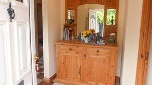 A wooden cabinet with a mirror above it, a vase with yellow flowers, and books on the shelf. - Borahard Lodge (Naas)