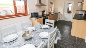 A modern kitchen with a dining area set for a meal. - Brynawel (Carmarthen)