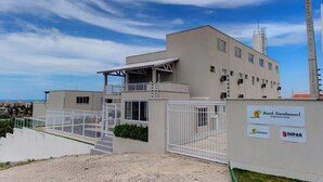 A modern building with a gated entrance, a covered outdoor area, and signage for Beach Townhouses I. - Excelente casa em Porto das Dunas (Aquiraz)