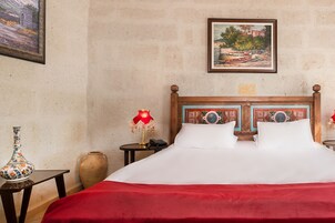 Habitación de hotel con una cama grande, una mesita de noche con lámpara, un florero y un cuadro en la pared.