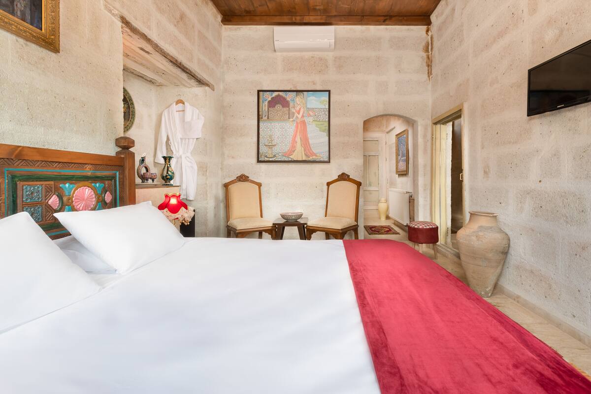Habitación de hotel con una cama grande, dos sillas, una mesa y un cuadro en la pared.