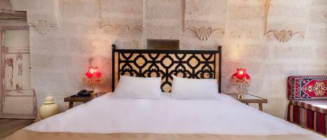 A bed with a black headboard, two bedside lamps, a nightstand, and a decorative wall.