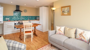 A compact living space with a kitchenette, a dining area, and a sofa with decorative pillows. - Roundham Cottage (Bridport)