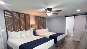 Una habitación de hotel con dos camas, un ventilador de techo, una lámpara y un armario.